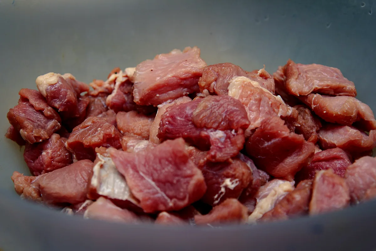 Cubes of raw beef in a heavy cooking pot