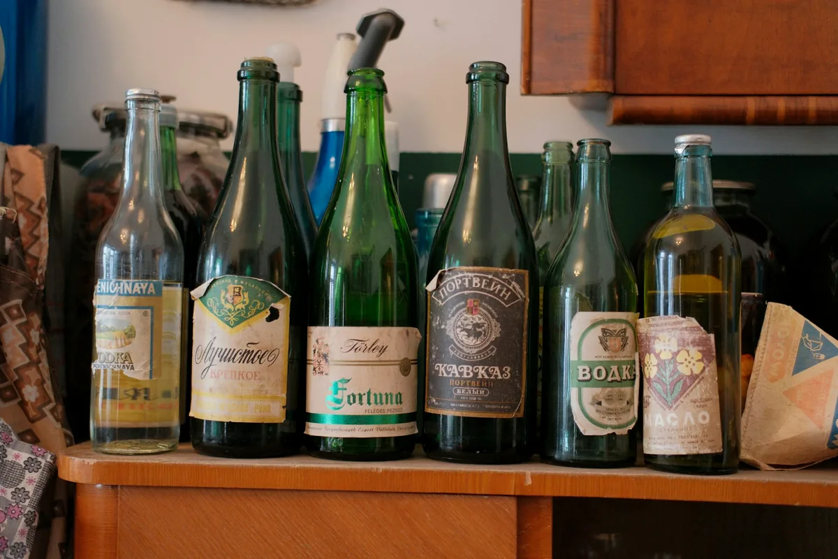 A row of old glass bottles with faded paper labels on a shelf