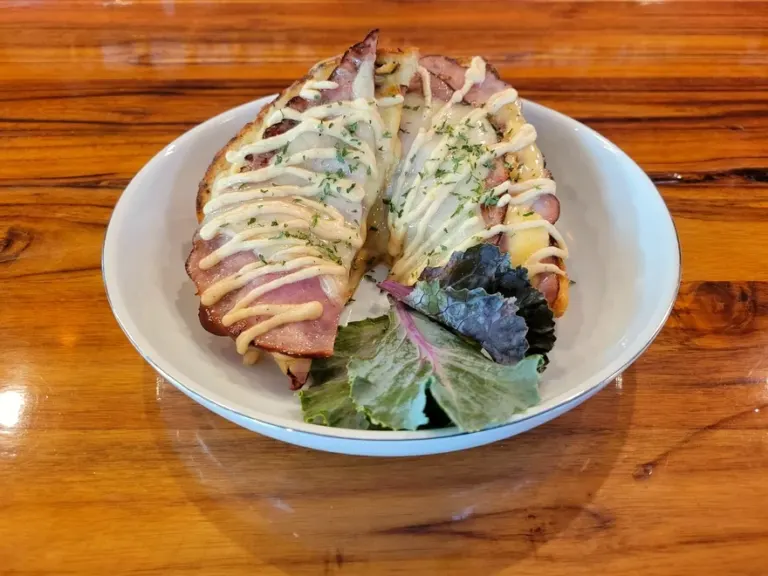A croque monsieur cut into fingers beside dressed salad leaves