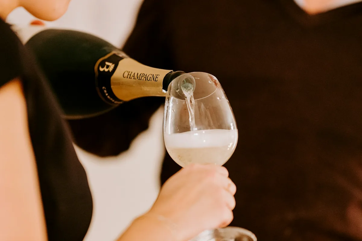 Sparkling wine being poured from a bottle into a held glass
