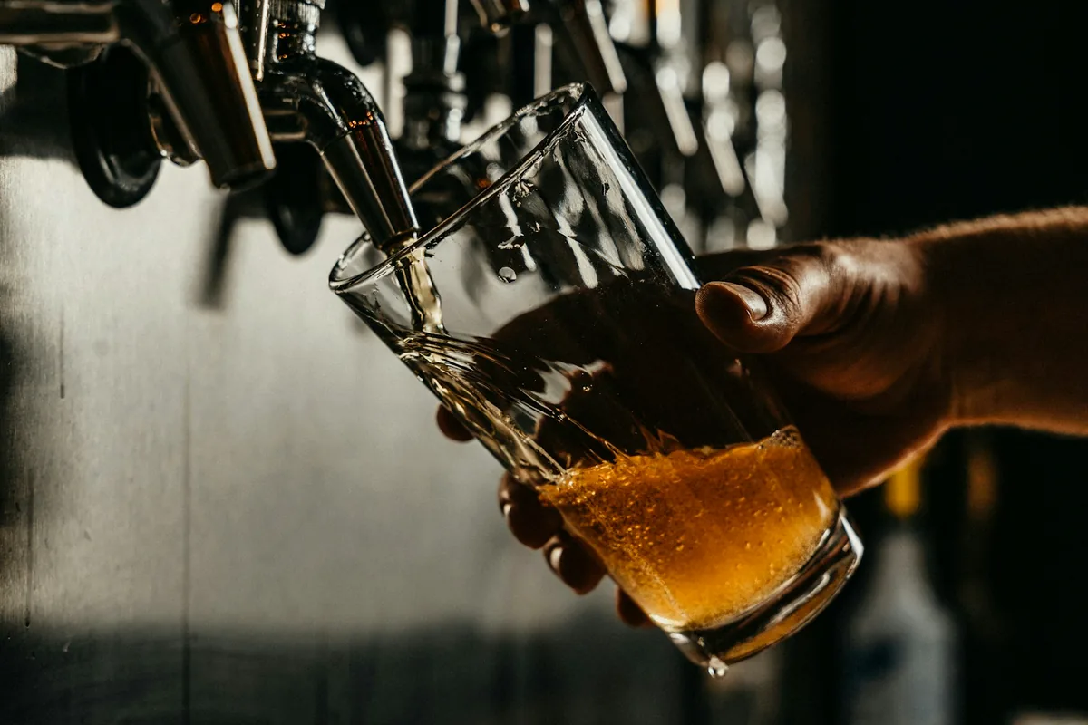 A pale beer being poured into a glass at a bar