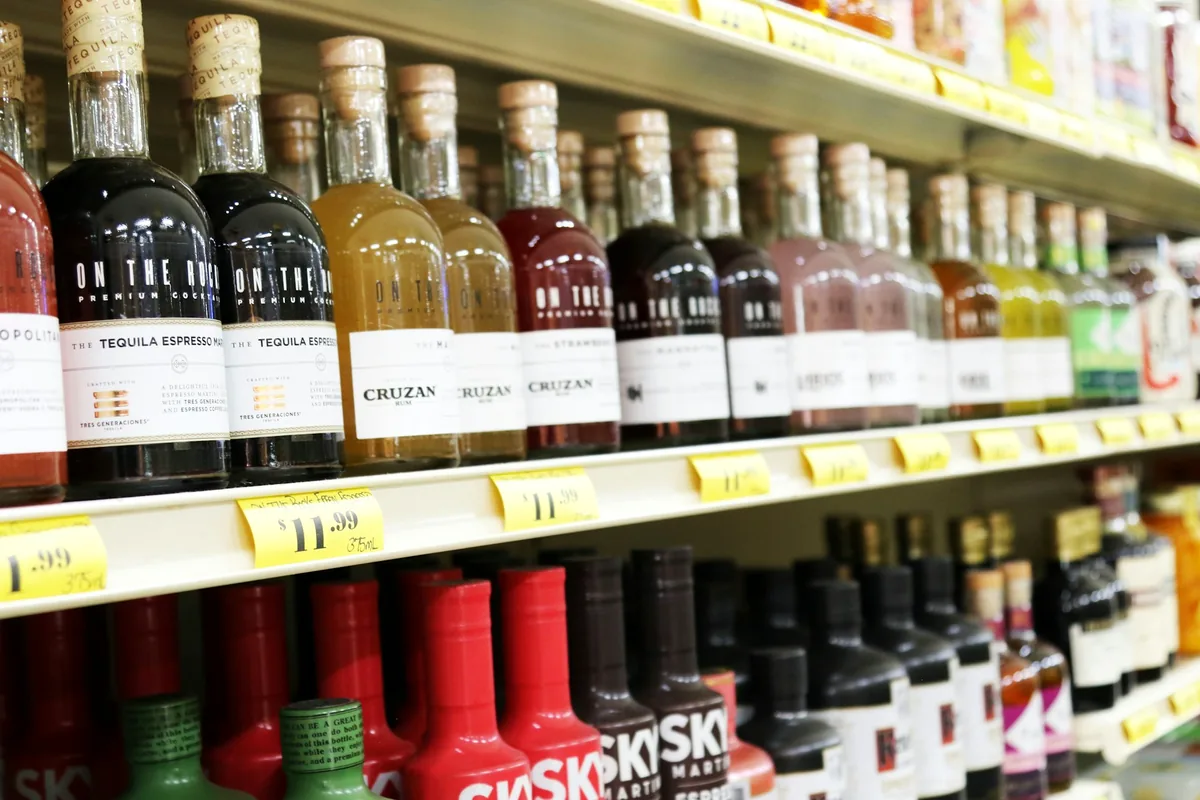 Bottles of spirits and liqueurs on a store shelf with price labels