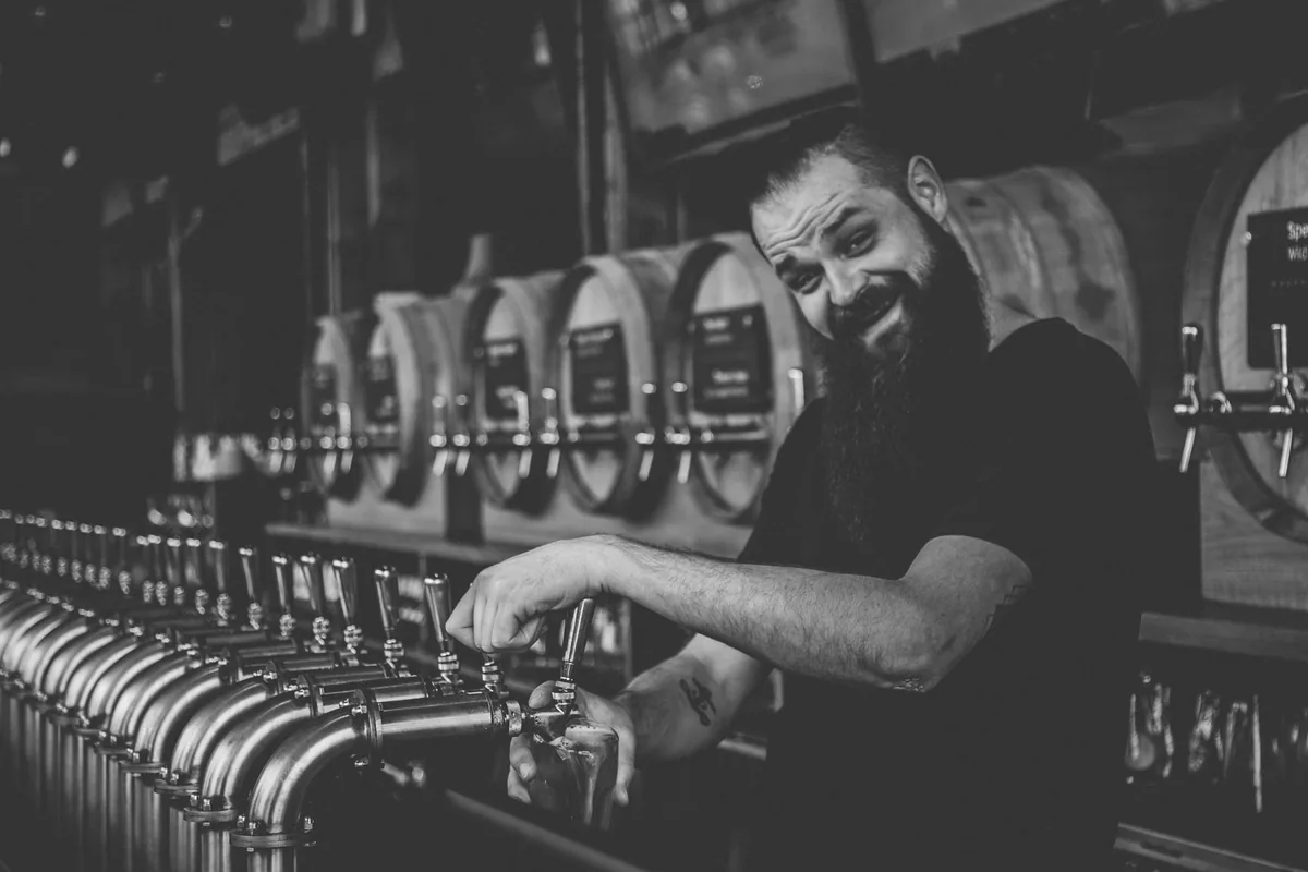 A bartender filling a glass from one of a long row of beer taps