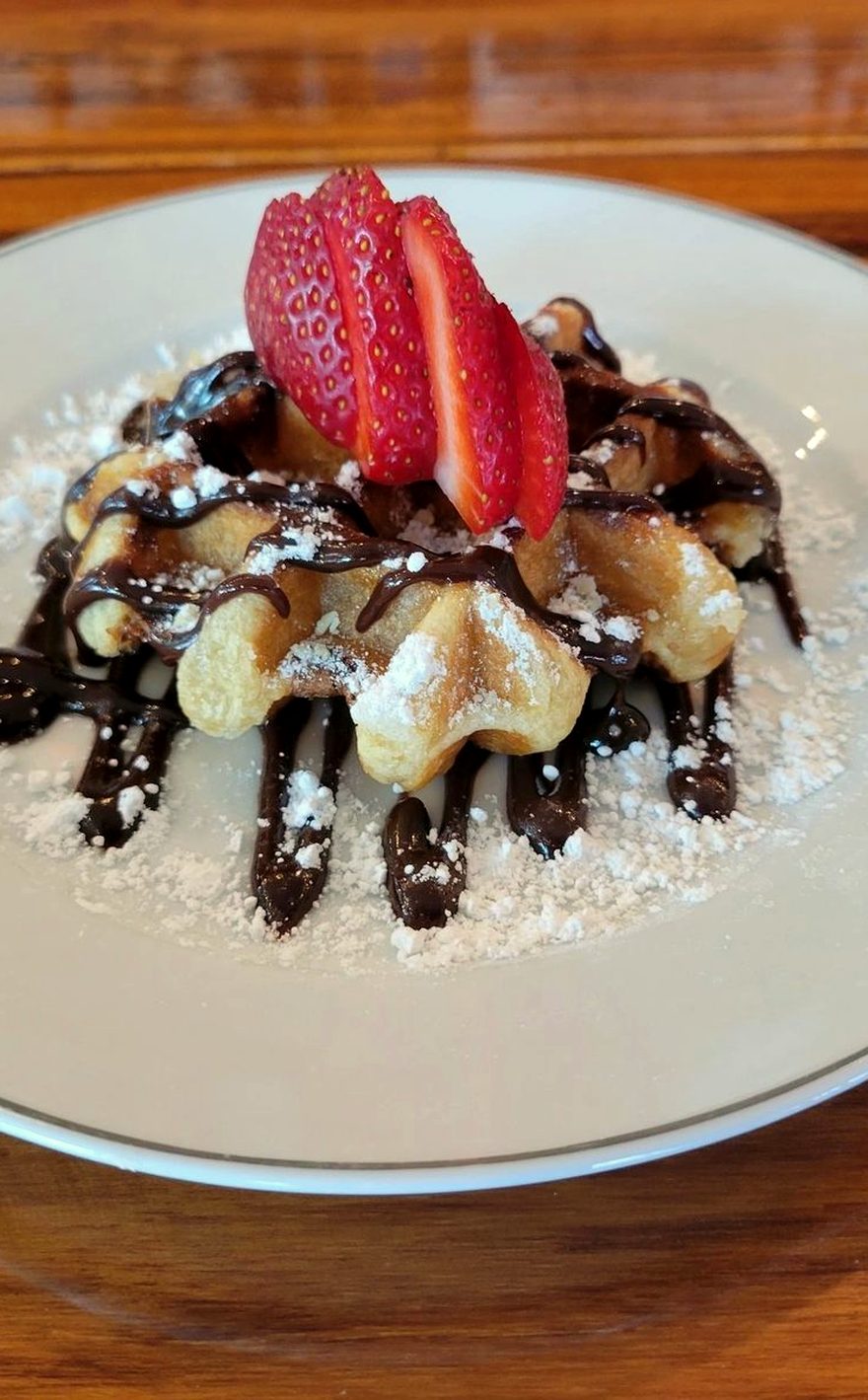 A Liege waffle at Meyboom Brasserie, dusted with sugar and finished with chocolate and sliced strawberries