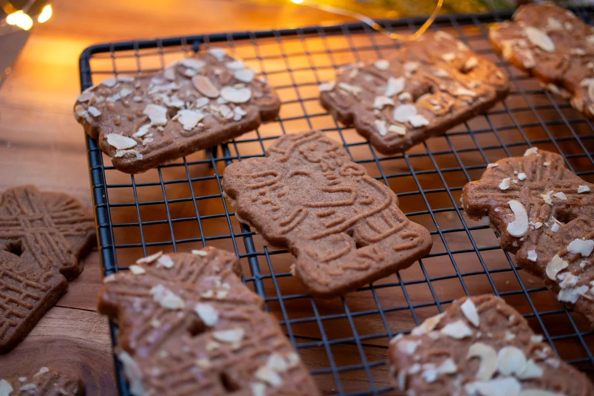 Stamped speculaas biscuits topped with flaked almonds cooling on a wire rack