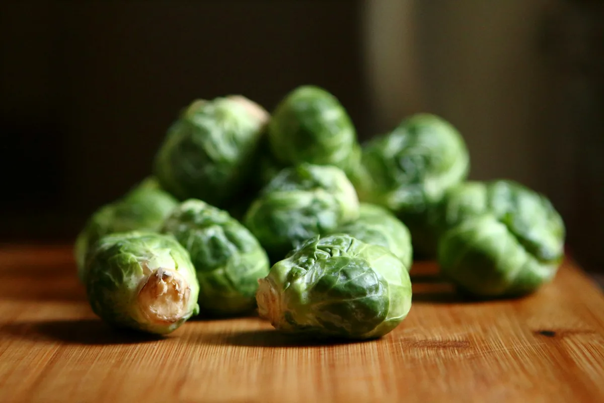 A small heap of Brussels sprouts on a dark wooden table