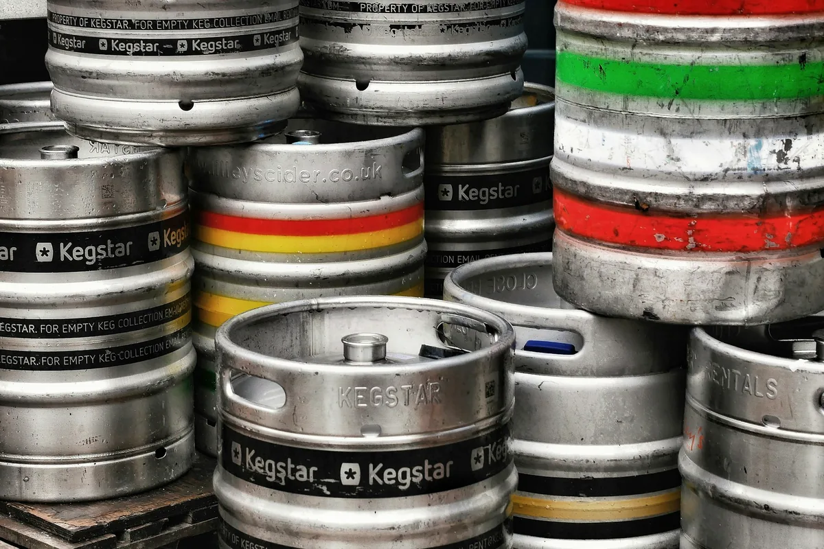 A stack of stainless steel beer kegs with coloured bands