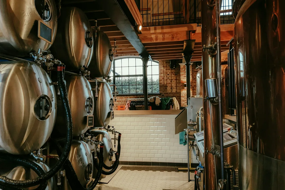 Copper and steel brewing vessels in a tiled brewhouse