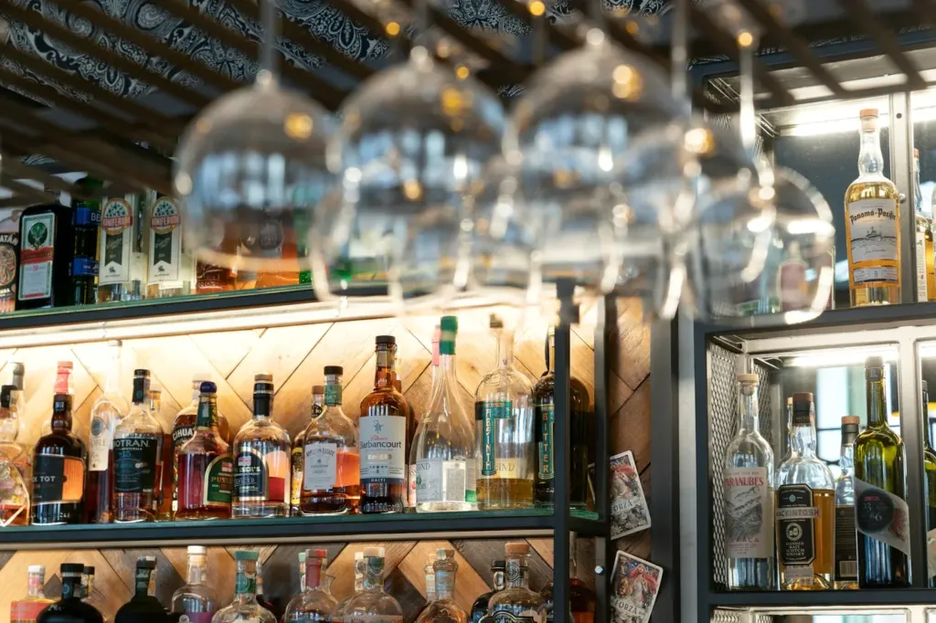 A bar backshelf stacked with spirit bottles under warm light