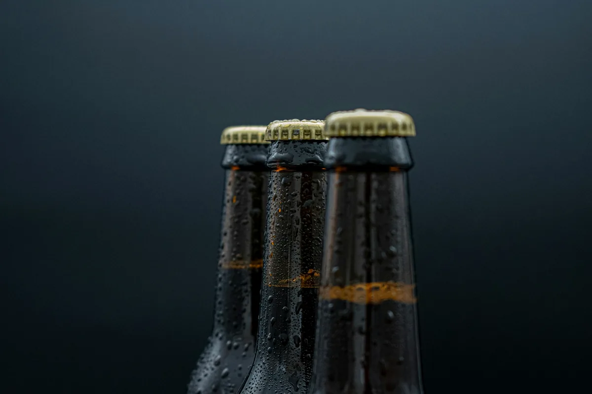 Three dark beer bottles with condensation against a dark background
