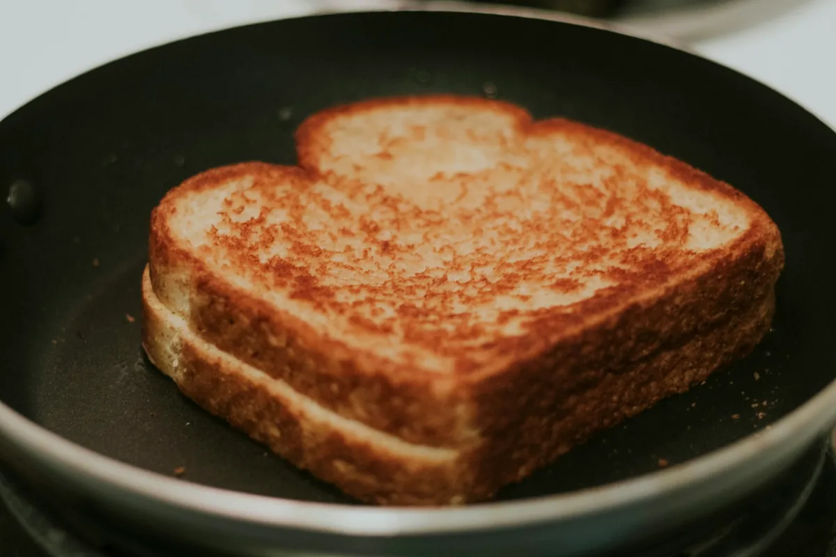 A grilled cheese sandwich browning in a frying pan