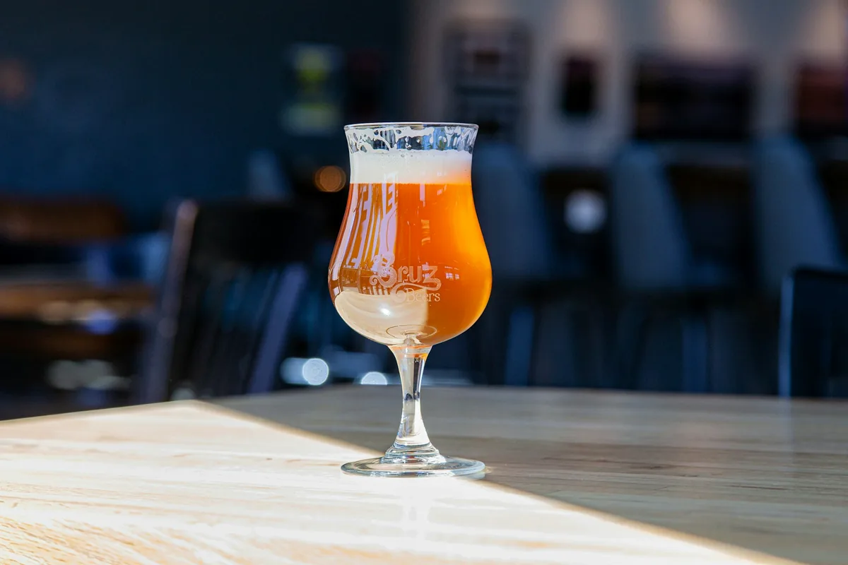 A footed tulip glass of amber beer on a bar table