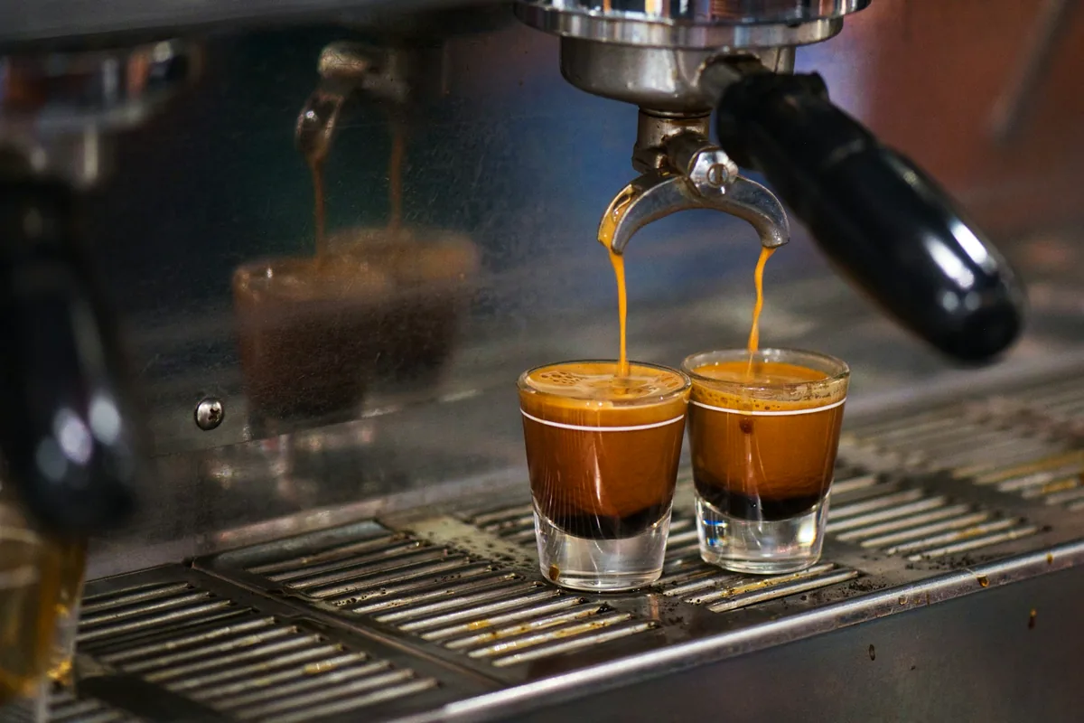 Two shots of espresso running from a machine into glasses