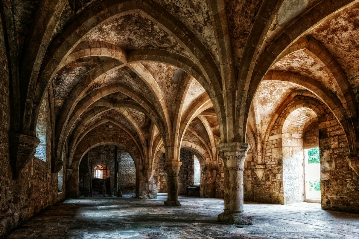 A vaulted stone undercroft with arched columns