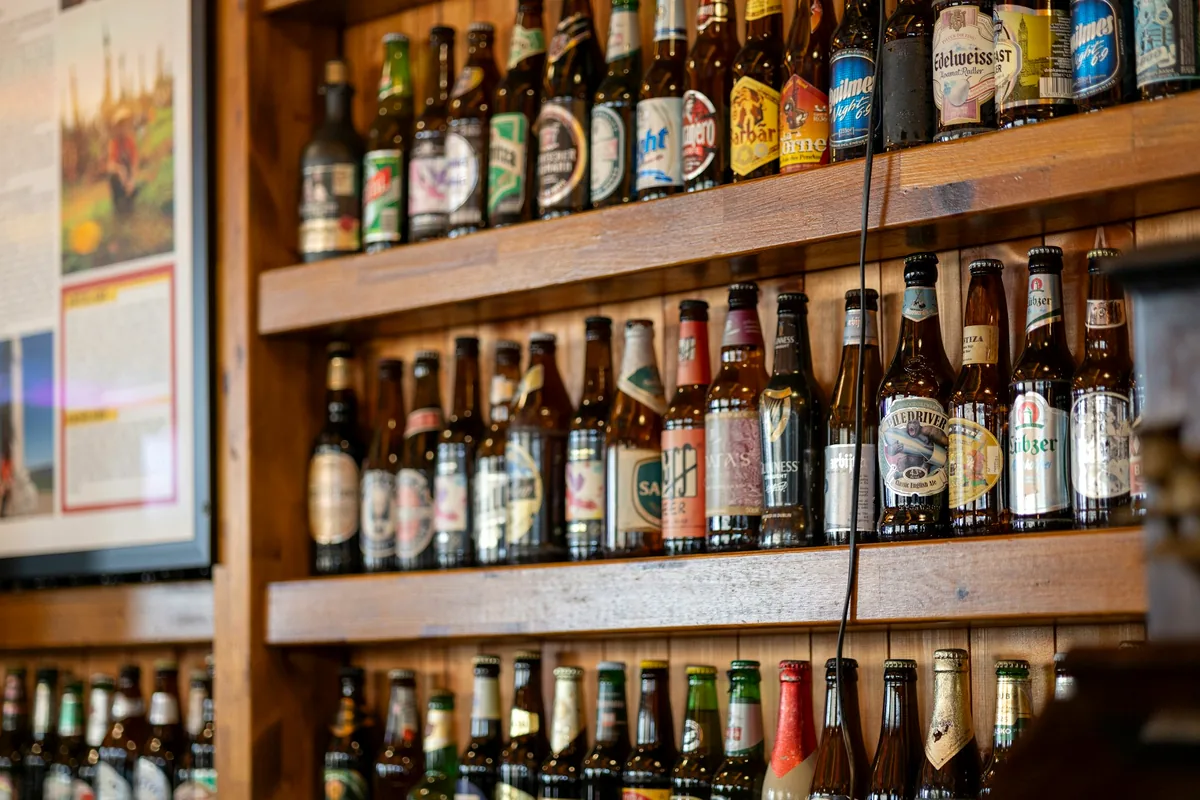 Shelves of assorted beer bottles filling a wall behind a bar