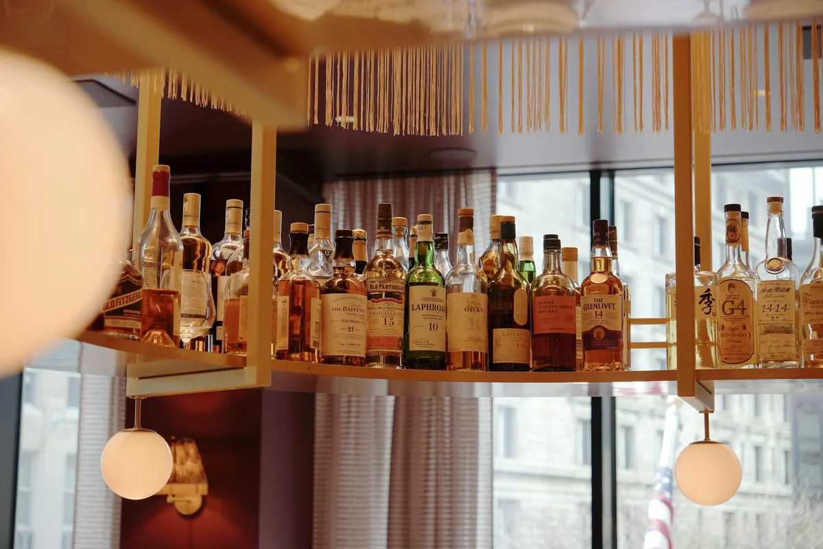 A display of whiskey and spirit bottles on lit shelves in a restaurant